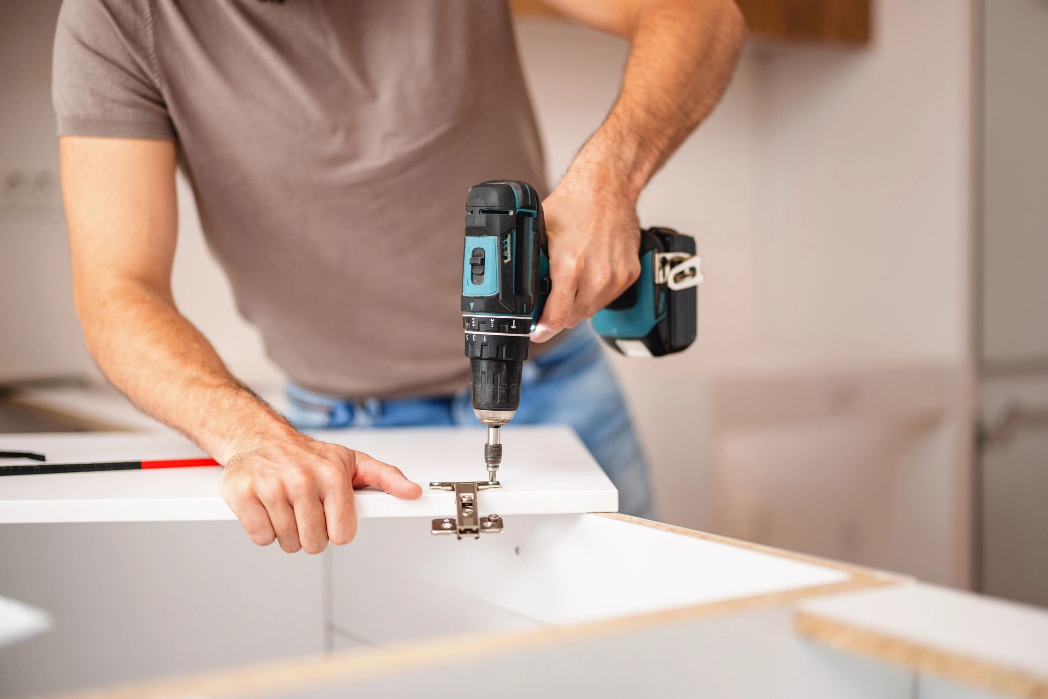 Carpenter using a power drill to fit kitchen cabinet