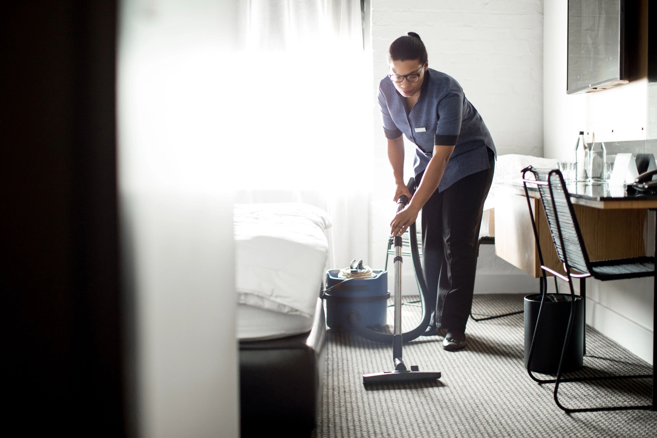 Cleaning service vacuuming carpet in a room