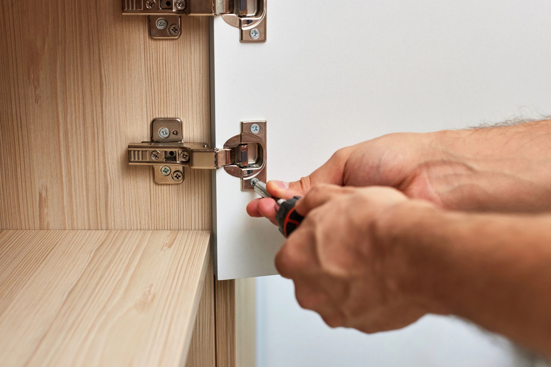 Handyman assembling cabinet and screwing door hinge